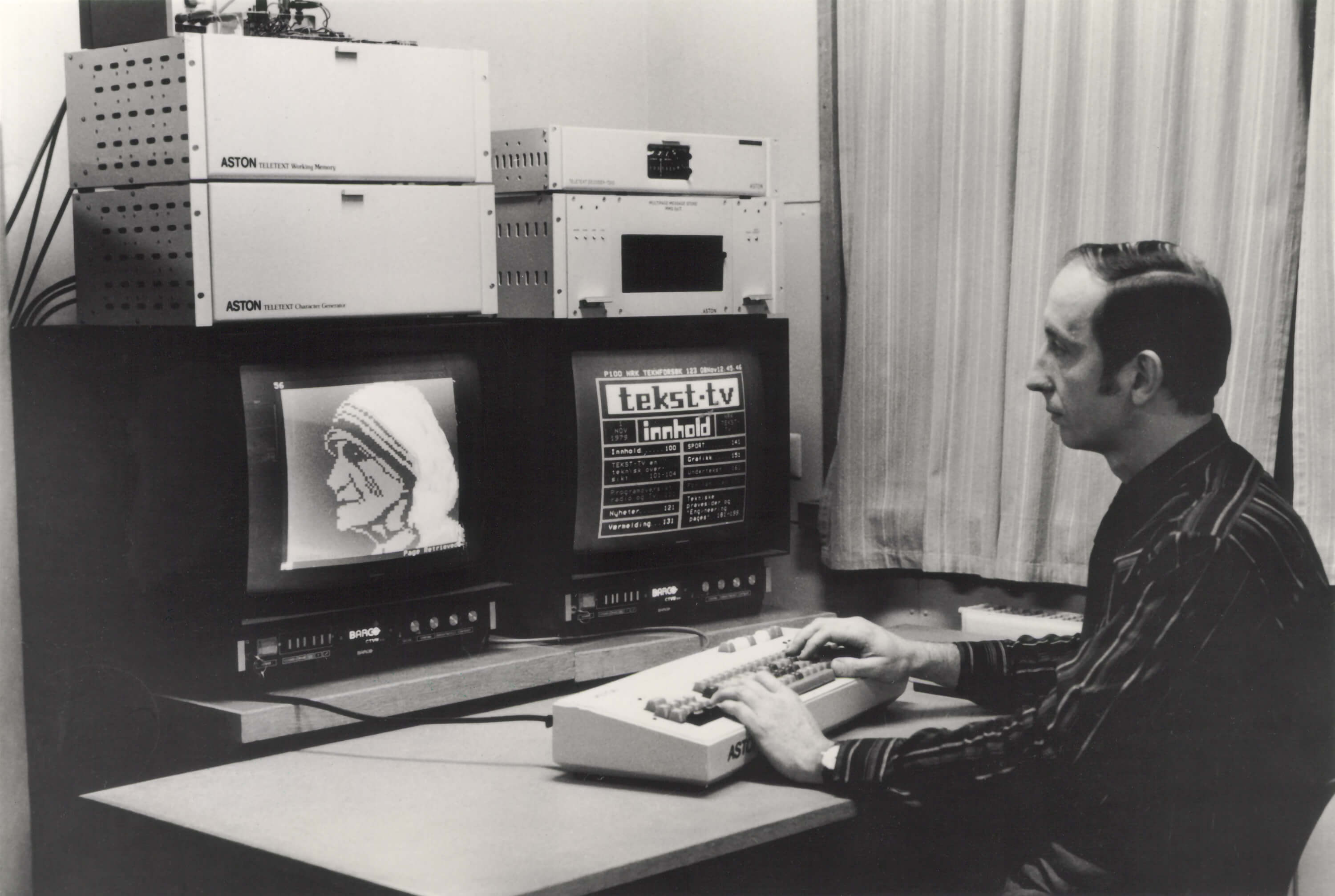 nrk tekst tv arbeider foran to skjermer som viser tekst og bilde grafikk